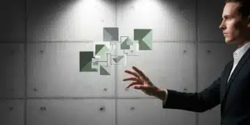 A person's hand reaching towards a fragmented digital projection on a concrete wall, symbolizing the effort to connect a distributed workforce and unify brand messaging amidst evolving work models.